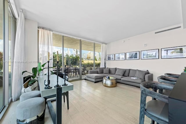 living room featuring a wall of windows and light hardwood / wood-style floors