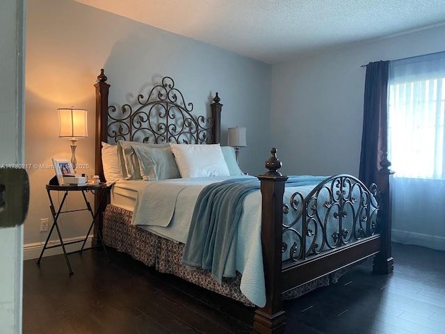 bedroom with a textured ceiling and dark hardwood / wood-style flooring