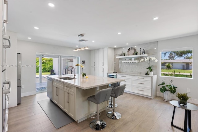 kitchen with french doors, white cabinetry, an island with sink, and sink