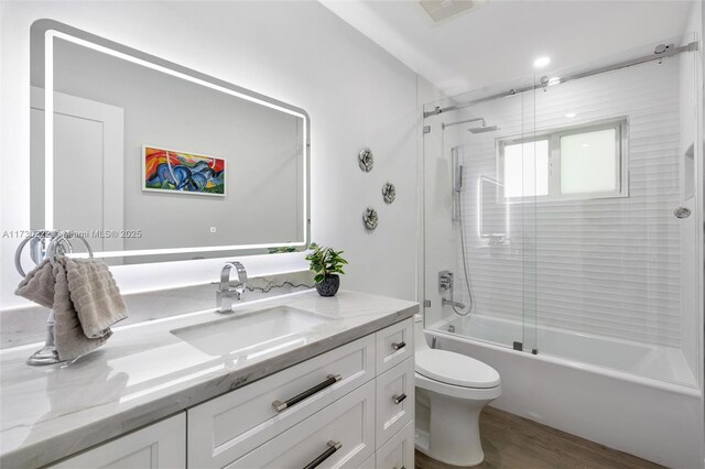 full bathroom featuring vanity, hardwood / wood-style floors, shower / bath combination with glass door, and toilet