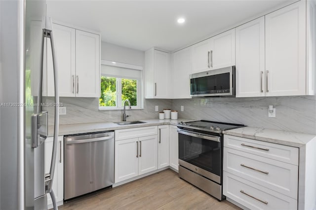 kitchen featuring white cabinetry, sink, decorative backsplash, light hardwood / wood-style floors, and stainless steel appliances