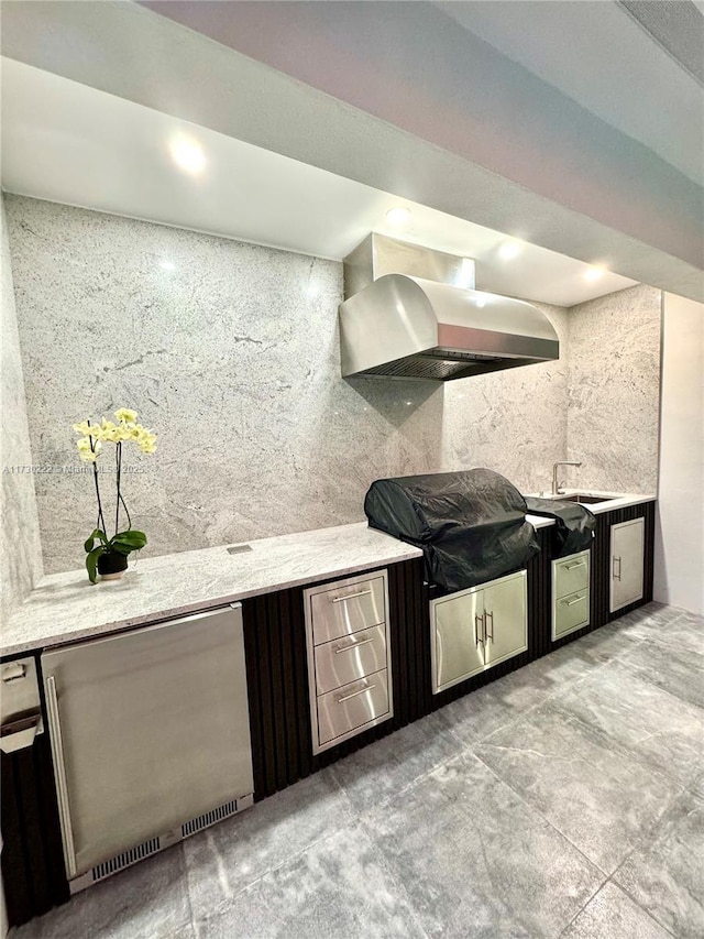 kitchen featuring sink, wall chimney exhaust hood, and refrigerator