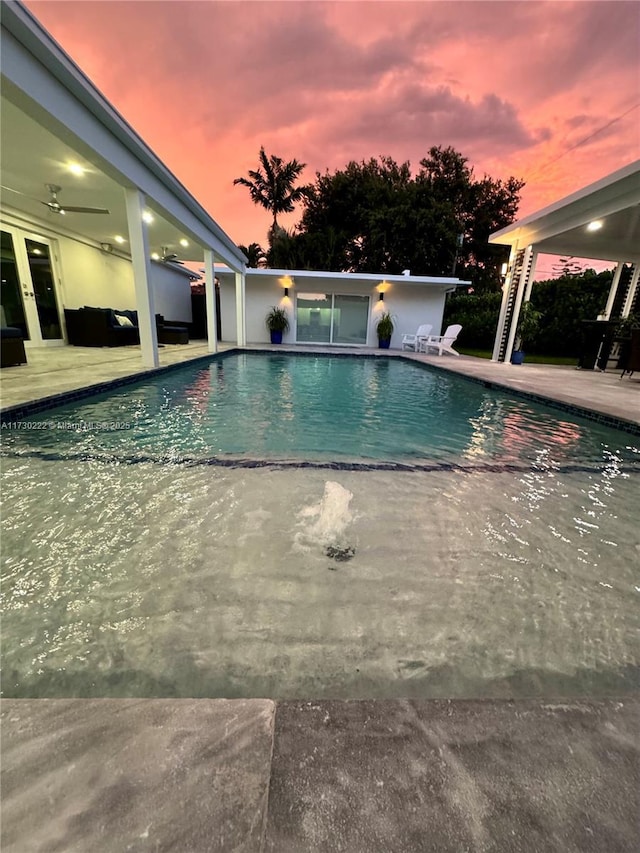 pool at dusk featuring a patio