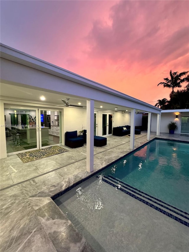 pool at dusk with a patio area