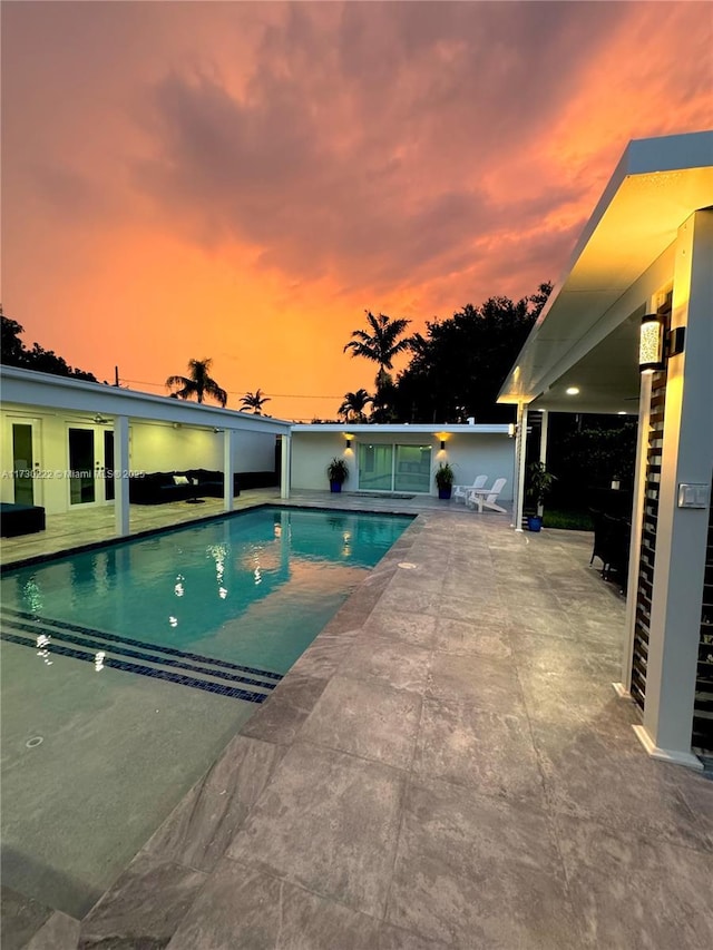 pool at dusk featuring a patio area