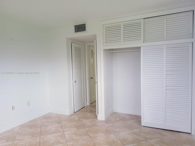 unfurnished bedroom with a closet, visible vents, baseboards, and light tile patterned floors