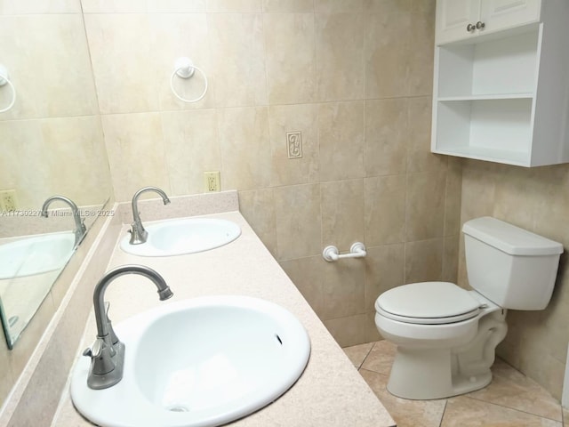 bathroom featuring tile patterned flooring, toilet, tile walls, and a sink