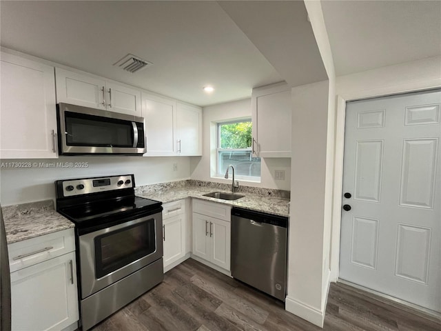 kitchen with white cabinetry, stainless steel appliances, sink, and light stone counters