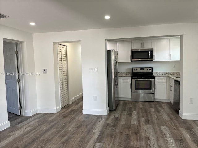 kitchen featuring white cabinetry, appliances with stainless steel finishes, dark hardwood / wood-style flooring, and light stone countertops