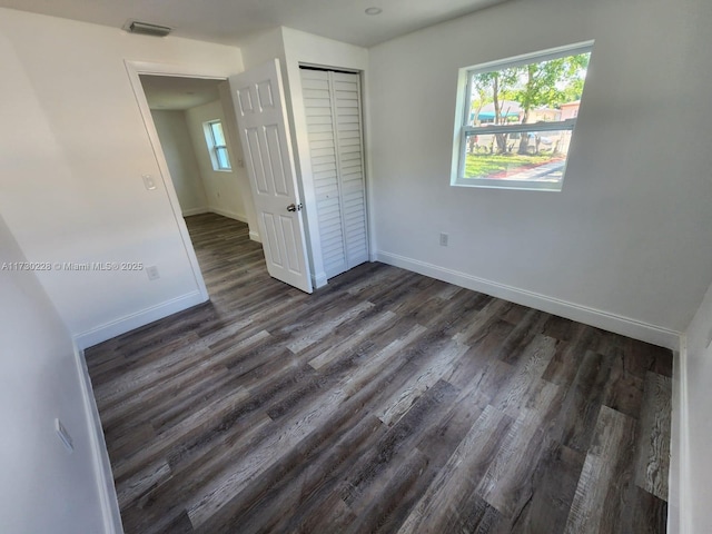 unfurnished bedroom with dark wood-type flooring and a closet