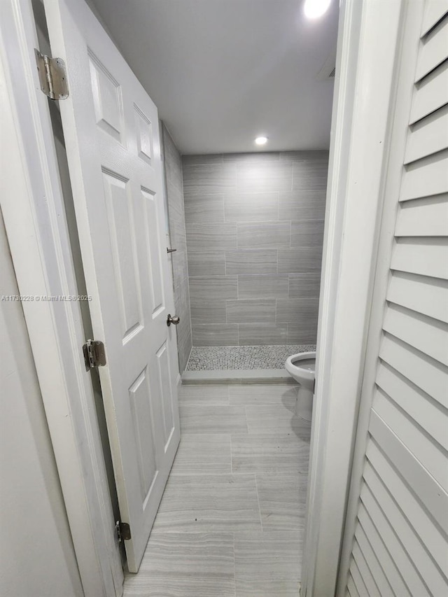 bathroom with tile patterned flooring, toilet, and tiled shower