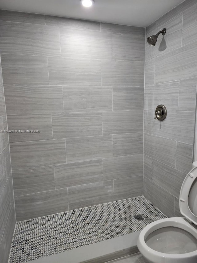 bathroom with tiled shower and toilet