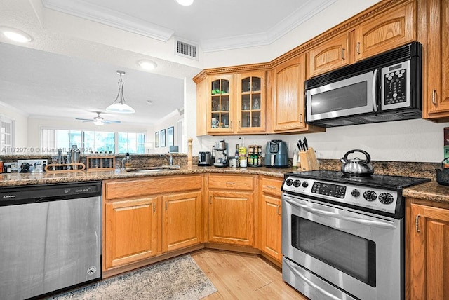 kitchen with dark stone countertops, sink, ornamental molding, light hardwood / wood-style floors, and stainless steel appliances