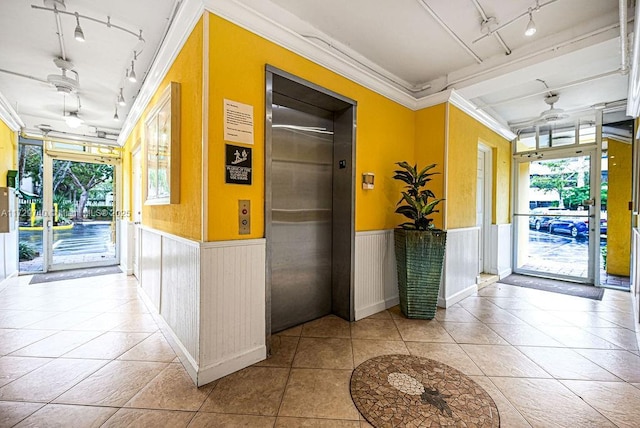 corridor featuring a wealth of natural light, light tile patterned floors, elevator, and crown molding