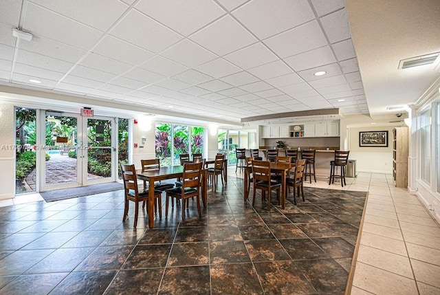 dining space with a drop ceiling and french doors