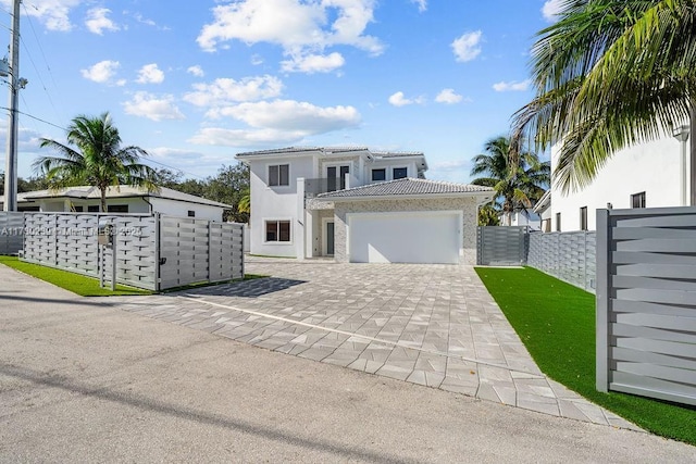 view of front of property with a fenced front yard, decorative driveway, stucco siding, an attached garage, and a tiled roof