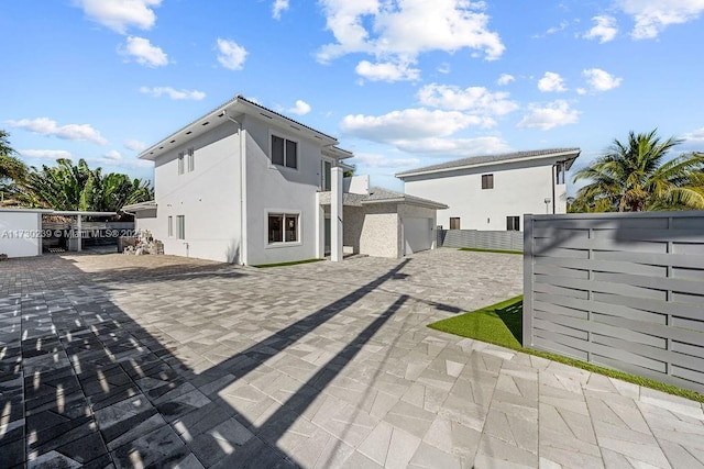 rear view of house with fence and stucco siding