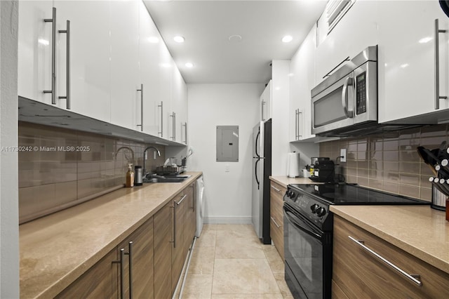 kitchen featuring tasteful backsplash, white cabinetry, sink, stainless steel appliances, and electric panel