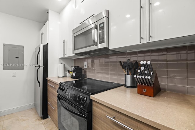 kitchen with appliances with stainless steel finishes, white cabinets, electric panel, tasteful backsplash, and light tile patterned flooring