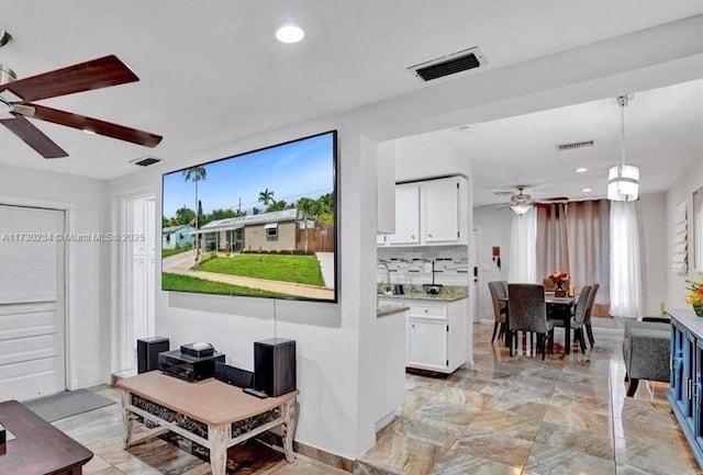 interior space with ceiling fan, white cabinets, decorative backsplash, and hanging light fixtures