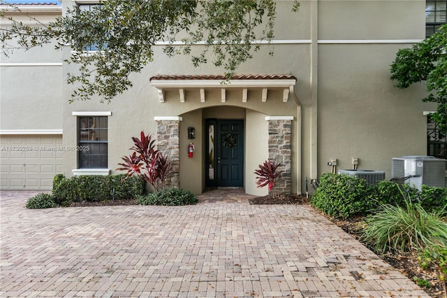 view of exterior entry featuring cooling unit and a garage