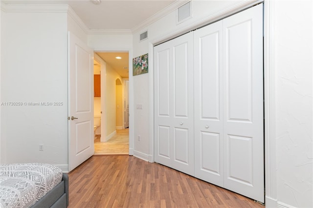 unfurnished bedroom with a closet, ornamental molding, and light hardwood / wood-style floors