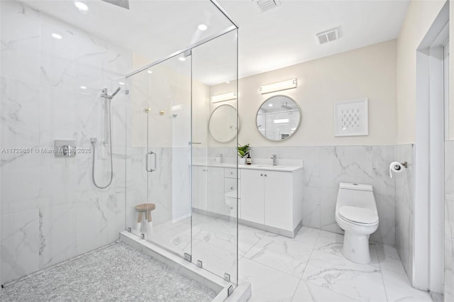 bathroom featuring tile walls, vanity, a shower with shower door, and toilet