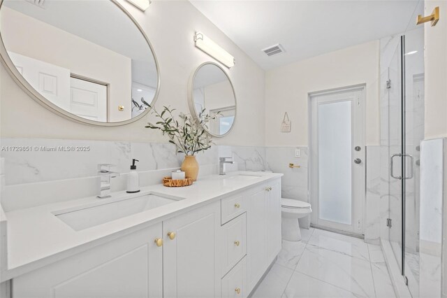 bathroom with vanity, toilet, a shower with door, and tile walls