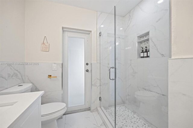 bathroom with walk in shower, vanity, toilet, and tile walls