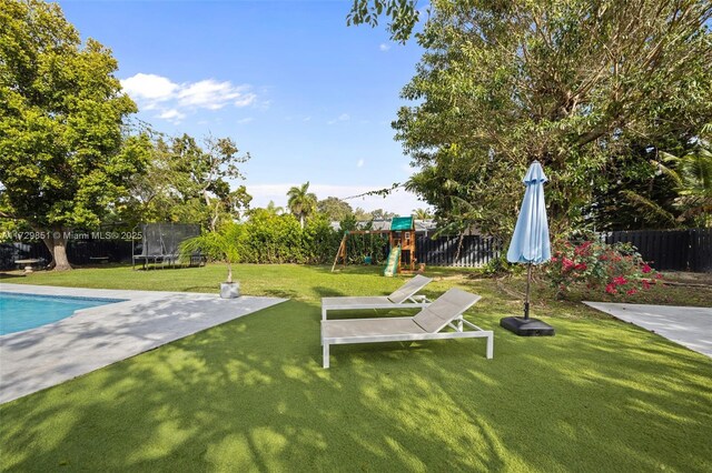 view of yard featuring a playground, a fenced in pool, a trampoline, and a patio area