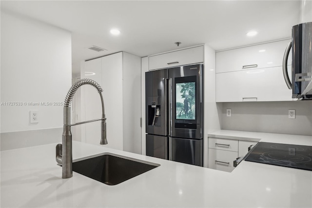 kitchen featuring range, sink, white cabinets, and fridge with ice dispenser