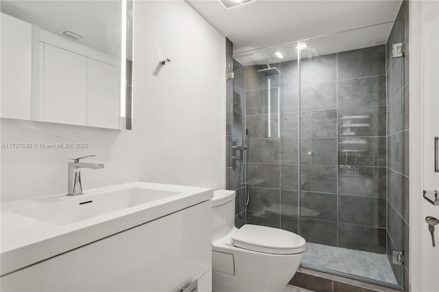 bathroom featuring a shower with shower door, toilet, and vanity