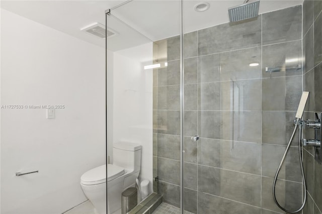 bathroom featuring tiled shower, toilet, and tile patterned floors