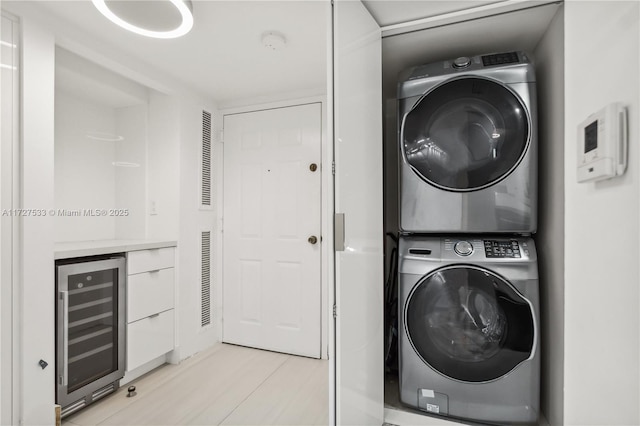 washroom featuring beverage cooler and stacked washing maching and dryer