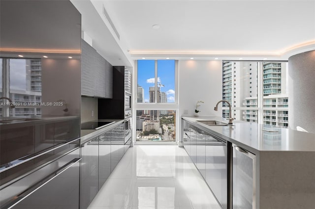 kitchen featuring sink, black electric stovetop, light tile patterned floors, floor to ceiling windows, and beverage cooler