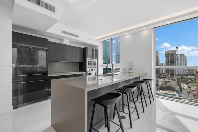 kitchen with floor to ceiling windows, sink, wall oven, and a breakfast bar area