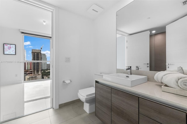 bathroom featuring a healthy amount of sunlight, toilet, tile patterned floors, and vanity