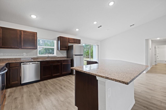 kitchen featuring a kitchen island, light hardwood / wood-style floors, vaulted ceiling, and stainless steel appliances