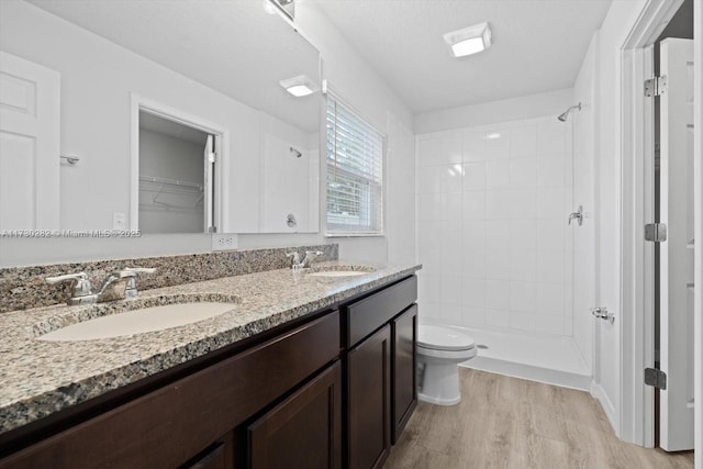 bathroom featuring tiled shower, hardwood / wood-style floors, a textured ceiling, toilet, and vanity