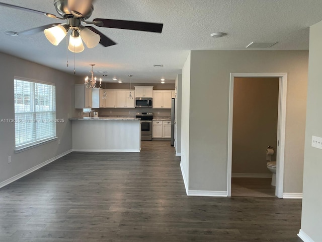 kitchen featuring appliances with stainless steel finishes, decorative light fixtures, dark wood-type flooring, white cabinetry, and kitchen peninsula