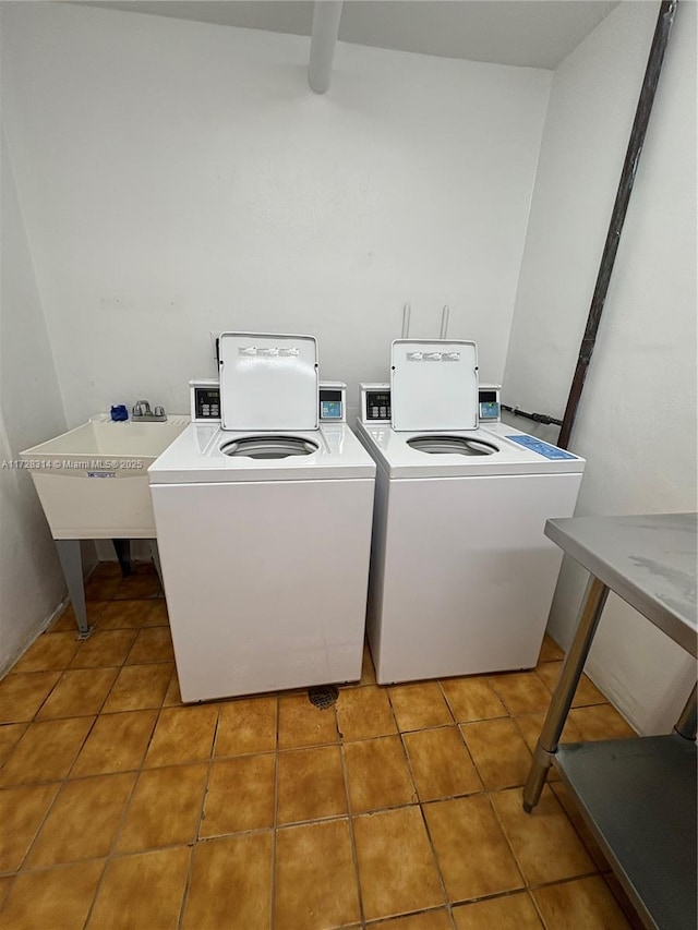 washroom with tile patterned flooring, washer and clothes dryer, and sink