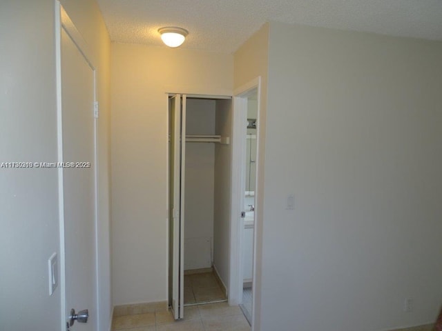 unfurnished bedroom featuring a closet, light tile patterned floors, and a textured ceiling