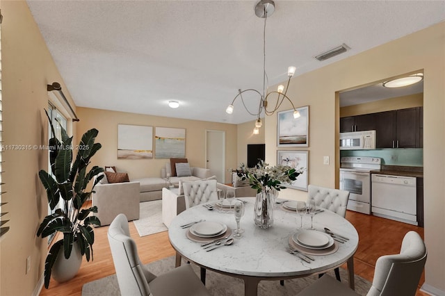 dining area featuring light wood-type flooring and a textured ceiling