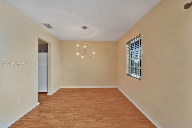 unfurnished dining area featuring a chandelier and light hardwood / wood-style floors