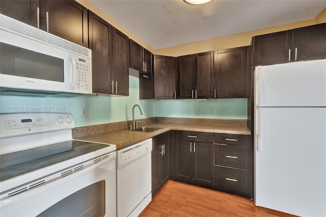 kitchen with sink, dark brown cabinets, white appliances, and light hardwood / wood-style flooring