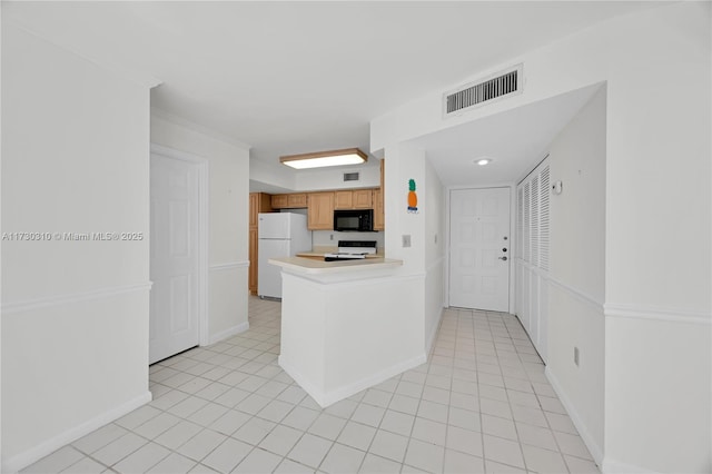 kitchen featuring visible vents, freestanding refrigerator, light countertops, black microwave, and range with electric stovetop