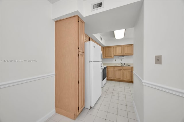 kitchen with light countertops, visible vents, light tile patterned floors, white appliances, and baseboards