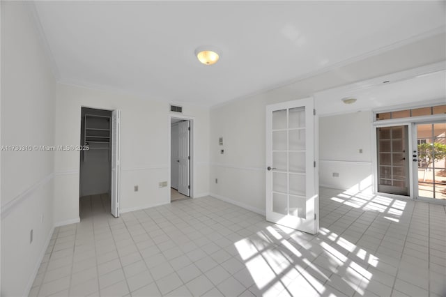 spare room featuring light tile patterned floors, baseboards, ornamental molding, and french doors