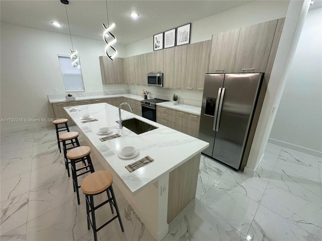 kitchen with light stone countertops, a kitchen bar, stainless steel appliances, hanging light fixtures, and a kitchen island with sink