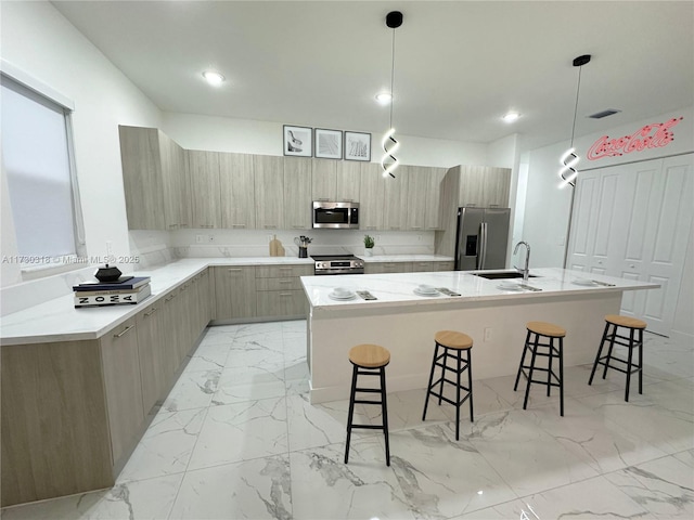 kitchen featuring decorative light fixtures, a center island with sink, and appliances with stainless steel finishes